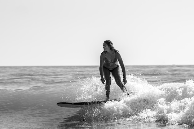 Scatto in scala di grigi di una bella giovane donna che pratica il surf