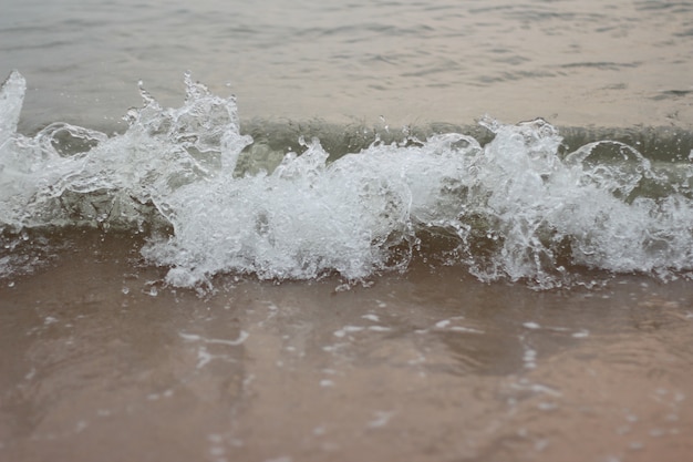 scatto istantaneo schiuma bianca onda di mare e sabbia