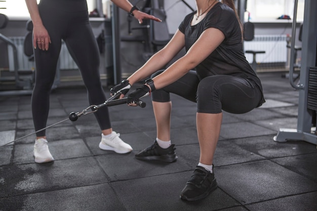 Scatto ritagliato di una donna che fa esercizio per i glutei in palestra con un personal trainer