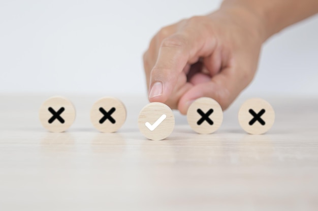 Scegli a mano il segno di spunta sul giocattolo di legno con il simbolo della croce per cambiare la mentalità vera o falsa o il modo di adattarsi per cambiare leader e trasformare la risposta del quiz e il concetto di sondaggio