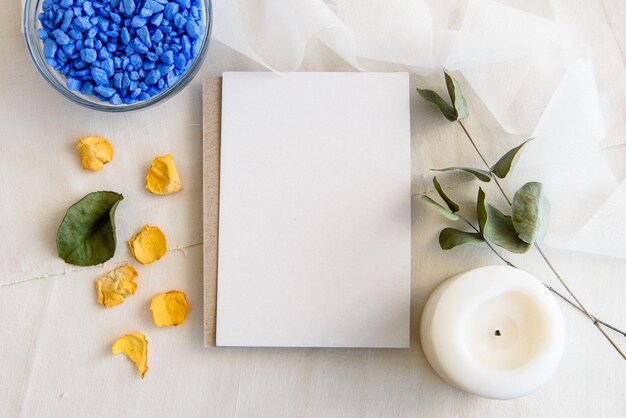 Scena di matrimonio estivo di un layout di cancelleria Un biglietto di auguri verticale vuoto una busta di carta artigianale e rami di ulivo isolati su uno sfondo bianco del tavolo Vista dall'alto dell'appartamento mediterraneo femminile