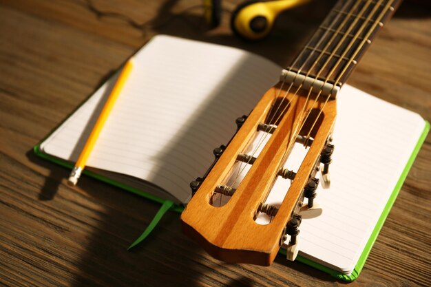 Scena di registrazione musicale con chitarra classica e cuffie sul primo piano del tavolo in legno