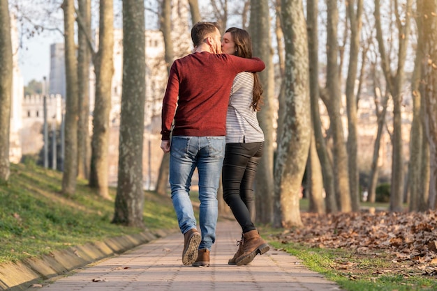 Scena felice e romantica con coppie di giovani uomini e donne che camminano e si baciano in un parco il giorno di san valentino