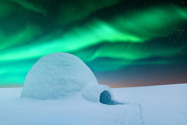 Scena invernale con luci polari luminose e igloo innevato