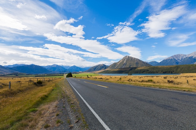 Scena rurale di Asphalt Road con il prato e la catena montuosa, isola del sud, Nuova Zelanda