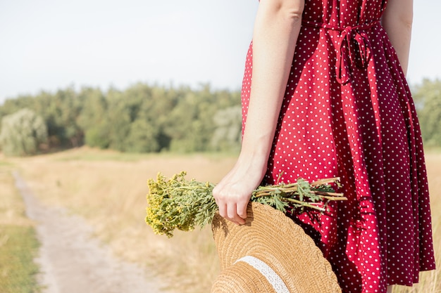 Scena rurale: femmina in abito a pois con cappello da contadino e bouquet in mano, vista ravvicinata