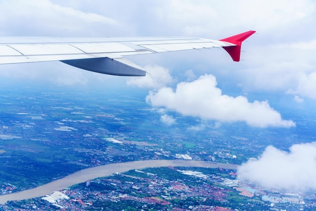 Scenario dalla finestra dell'aeroplano che vede l'ala delle nuvole bianche dell'aeroplano, il cielo blu e il paesaggio di Bangkok, Tailandia