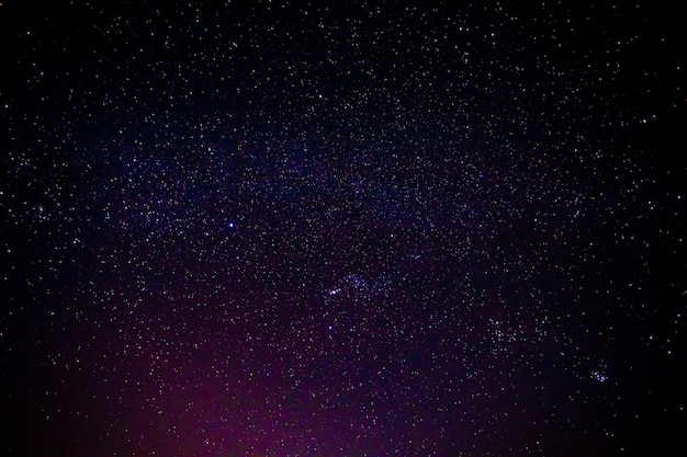 Scenario notturno con la Via Lattea colorata e gialla piena di stelle nel cielo.