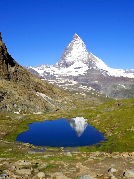 Scenica panoramica del lago e delle montagne di Matterhorn contro un cielo blu limpido