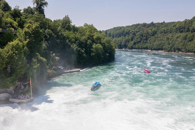 Schaffhausen, Svizzera - 22 giugno 2017: Barca con persone che galleggiano alla cascata delle cascate del Reno. È una delle principali attrazioni turistiche. Giornata estiva con cielo azzurro