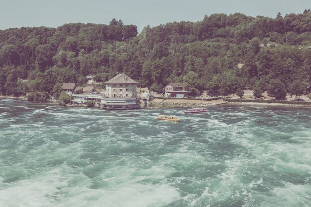 Schaffhausen, Svizzera - 22 giugno 2017: Barca con persone che galleggiano alla cascata delle cascate del Reno. È una delle principali attrazioni turistiche. Giornata estiva con cielo azzurro