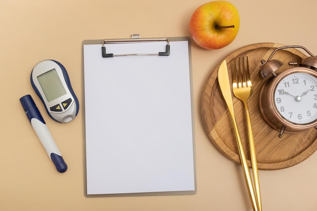 Scheda di testo vuota e glucometro e posate con sveglia su piatto vista dall'alto a disposizione Mock up tema diabete