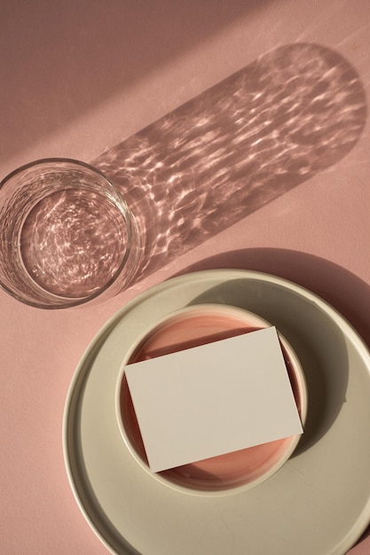 Scheda foglio di carta bianca con spazio per la copia mockup Modello di marchio aziendale estetico di lusso minimo Vetro con ombre di luce solare lastre di ceramica su sfondo rosa polveroso Vista dall'alto piatta