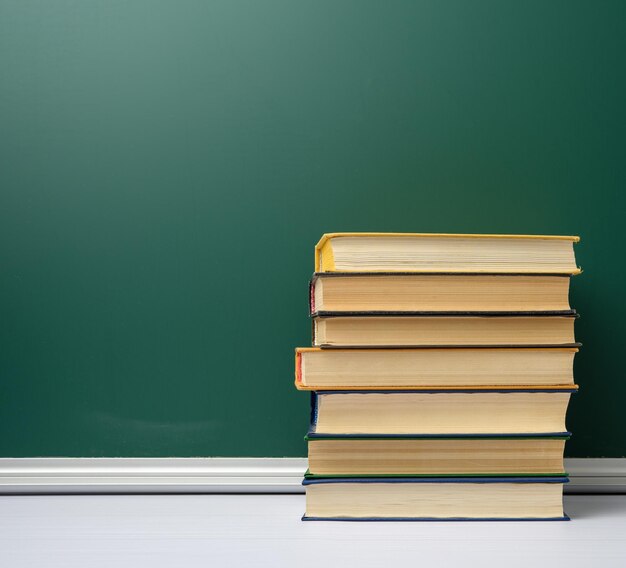 Scheda scolastica bianca di gesso verde e pila di libri di ritorno a scuola spazio di copia