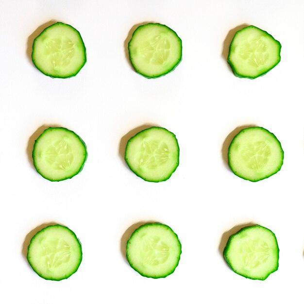 Schema ripetuto di semicerchi affettati di cetrioli vegetali crudi freschi per insalata isolato su uno sfondo bianco piatto, vista dall'alto. quadrato