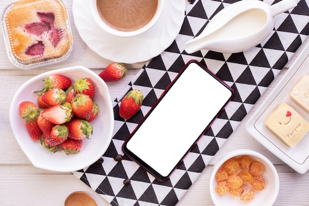 Schermo bianco su smartphone, cellulare, tablet con dessert dolce e fragole