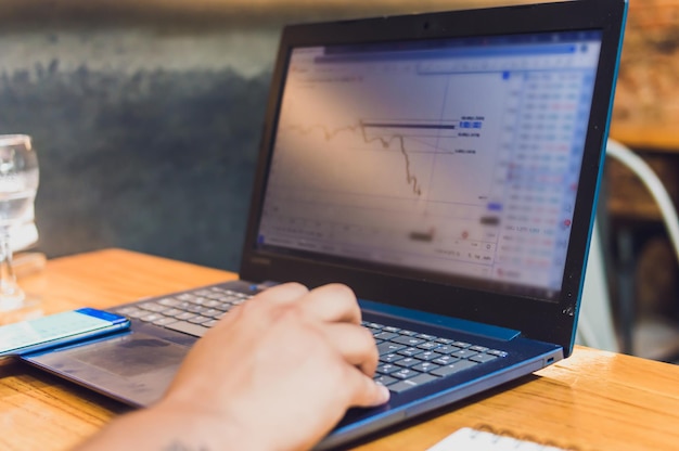 Schermo del laptop con grafici finanziari e trading all'interno di un ristorante