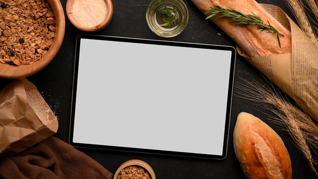 Schermo del tablet mockup con farina di pane al forno con pane francese cereali integrali su sfondo nero