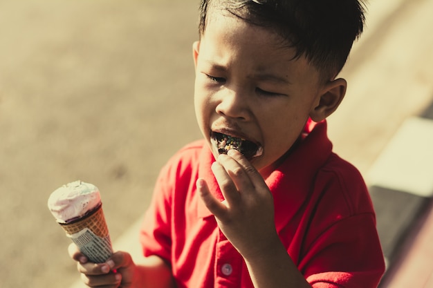 Scherzi il cibo del gelato nel cono delle cialde e sbattere le palpebre sul fondo all&#39;aperto del parco.