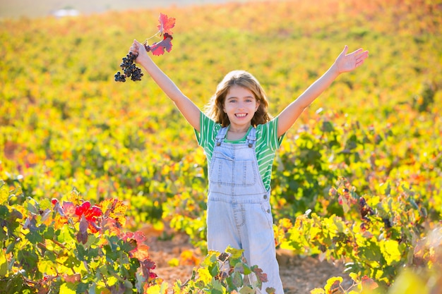 Scherzi la ragazza nel mazzo felice dell&#39;uva rossa delle armi di campo aperto della vigna di autunno