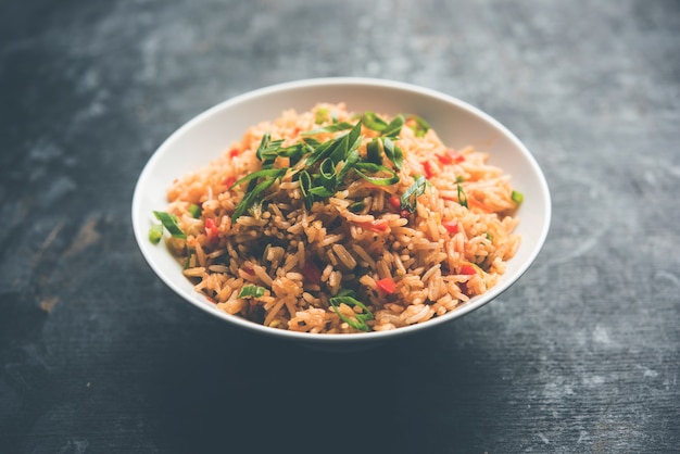 Schezwan Fried Rice Masala è un popolare cibo indo-cinese servito in un piatto o in una ciotola con le bacchette. messa a fuoco selettiva