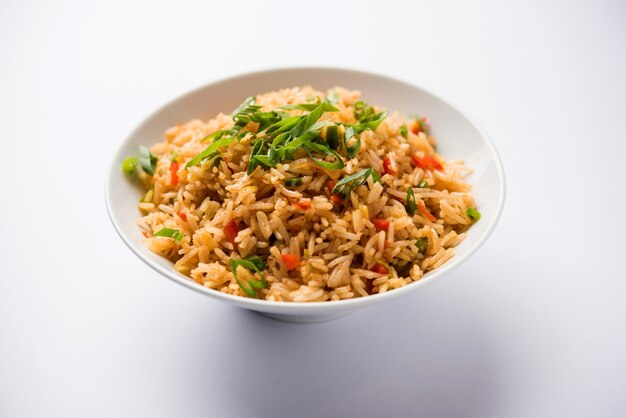 Schezwan Fried Rice Masala è un popolare cibo indo-cinese servito in un piatto o in una ciotola con le bacchette