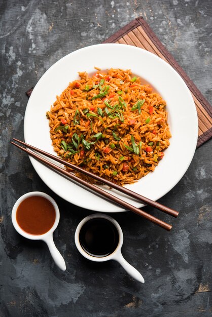 Schezwan Fried Rice Masala è un popolare cibo indo-cinese servito in un piatto o in una ciotola con le bacchette