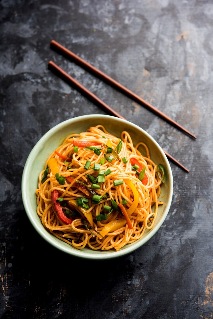 Foto schezwan noodles o verdure hakka noodles o chow mein è una popolare ricetta indo-cinese, servita in una ciotola o in un piatto con bacchette di legno. messa a fuoco selettiva