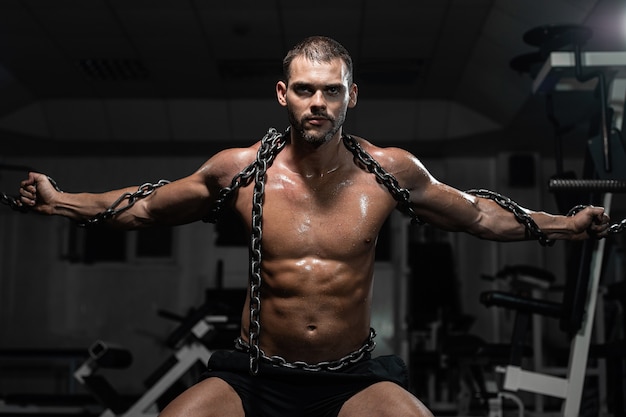 Schiavo muscoloso uomo in catene in palestra, il prigioniero