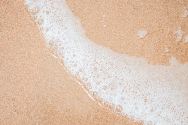 Schiuma bianca sulla sabbia della spiaggia