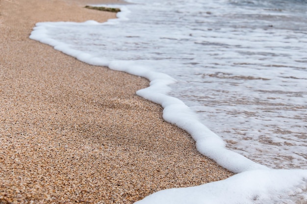 Schiuma dalle onde sulla spiaggia del mare