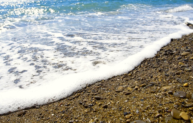 Schiuma delle onde del mare su una spiaggia di ciottoli