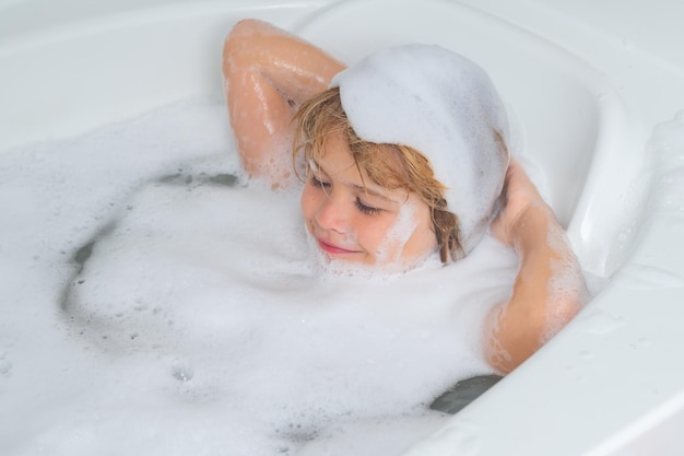 Schiuma di shampoo per bambini sulla testa del bambino bambino con schiuma di shampoo e bolle sui capelli che fanno il bagno faccia buffa o