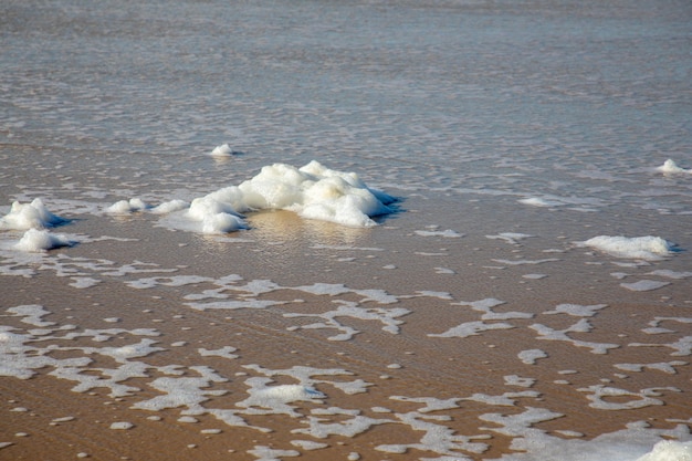 Schiuma sulla spiaggia di sabbia acqua di mare e vento bassa marea