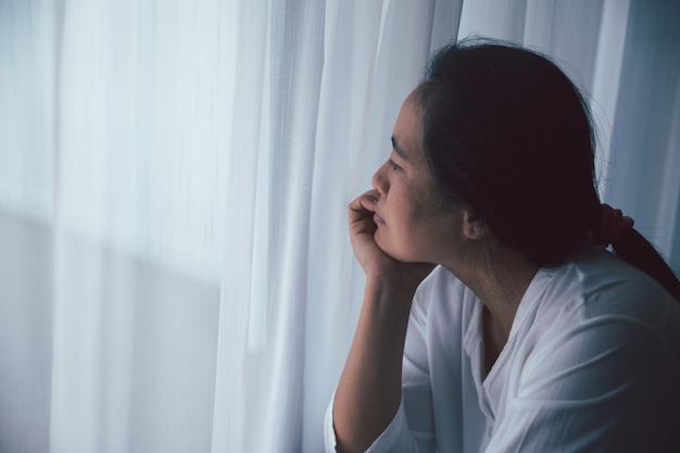 Schizofrenia con solitudine e tristezza nel concetto di depressione per la salute mentale Donna depressa seduta contro il pavimento a casa con una stanza buia che si sente infelice Le donne sono depresse, timorose e infelici