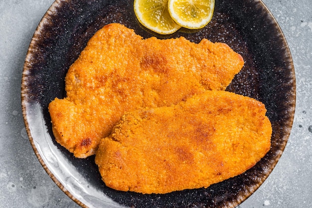 Schnitzel weiner tedesca impanata arrosto su un piatto Sfondo grigio Vista dall'alto