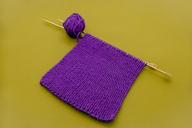 sciarpa a maglia viola con ferri da maglia diversi oggetti sfondo giallo