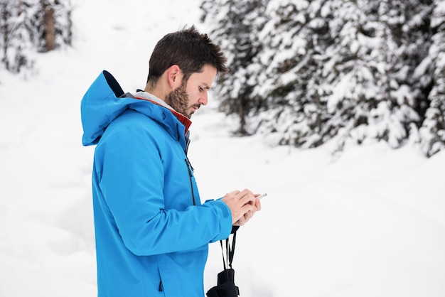 Sciatore che per mezzo del telefono cellulare sulle montagne nevose