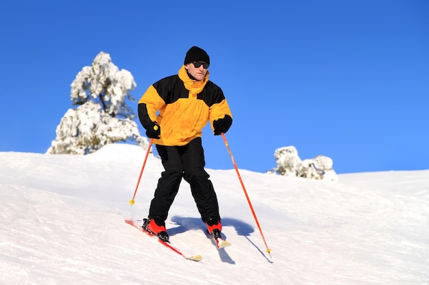 Sciatore che scia in discesa in alta montagna contro il sole