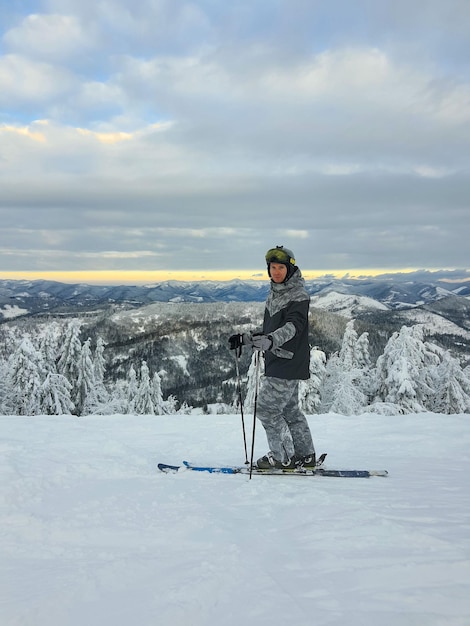 Sciatore dell'uomo che gode del tramonto sopra lo sport invernale delle montagne