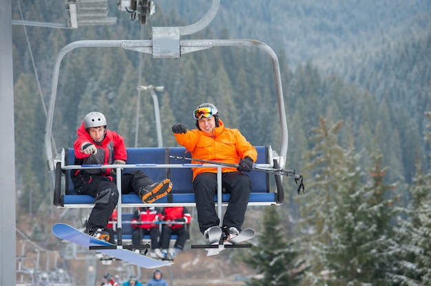 Sciatore e snowboarder in sella agli impianti di risalita