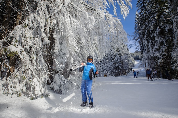 Sciatore felice della donna su una pista da sci nella foresta