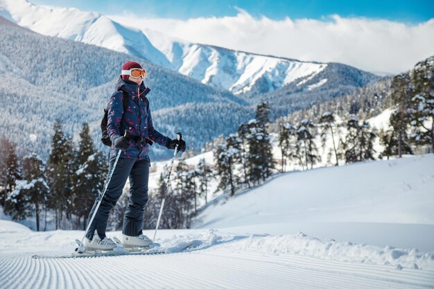 Sciatore femminile che gode della vista delle montagne sul pendio di velluto in una giornata di sole in una stazione sciistica