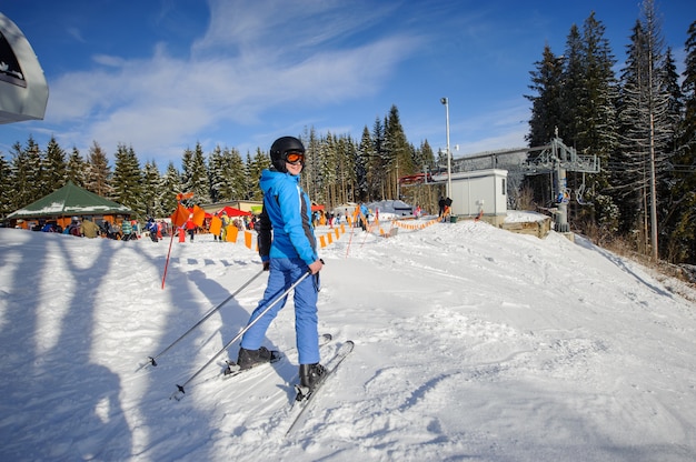 Sciatore femminile sulla cima della pista da sci con ski-lift