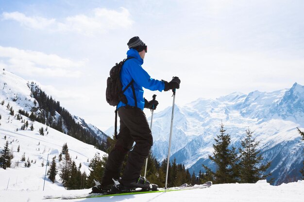 Sciatore in cima a una montagna con vista sulle Alpi sullo sfondo