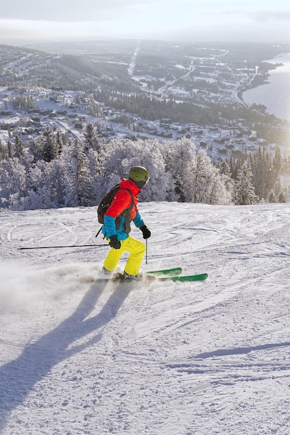 Sciatore in montagna pista preparata e giornata di sole per il tempo libero invernale sport e concetto di persone