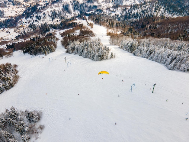 Sciatore parapendio sopra la pista da sci di montagna sport estremo