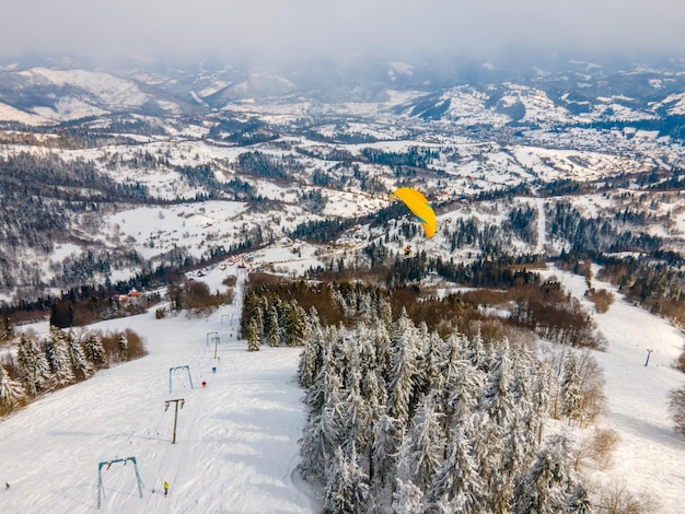 Sciatore parapendio sopra la pista da sci di montagna sport estremo