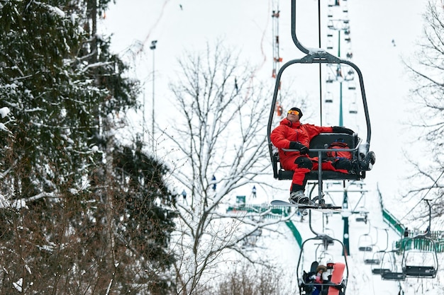 Sciatore seduto all'impianto di risalita in alta montagna durante la giornata di sole. Sport invernali e ricreazione, attività ricreative all'aperto.