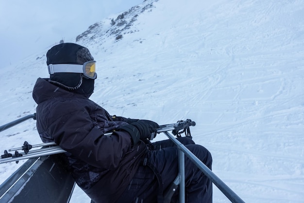 Sciatore seduto sulla seggiovia che ti porta in alta montagna per sciare nei Pirenei Grandvalira Andorra